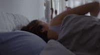 a woman laying in bed with her head on the pillow
