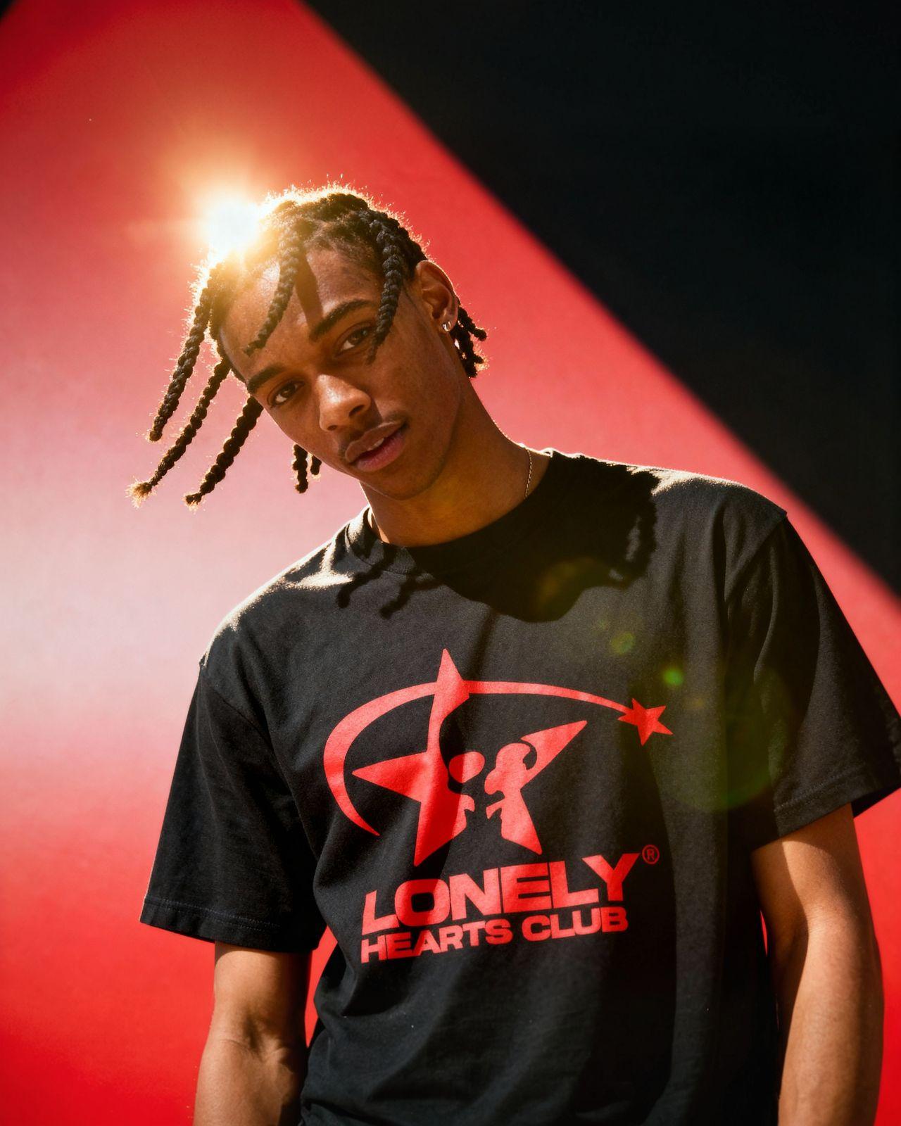 a man with dreadlocks standing in front of a red wall