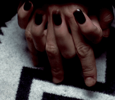 a close up of a person's hands with black nail polish