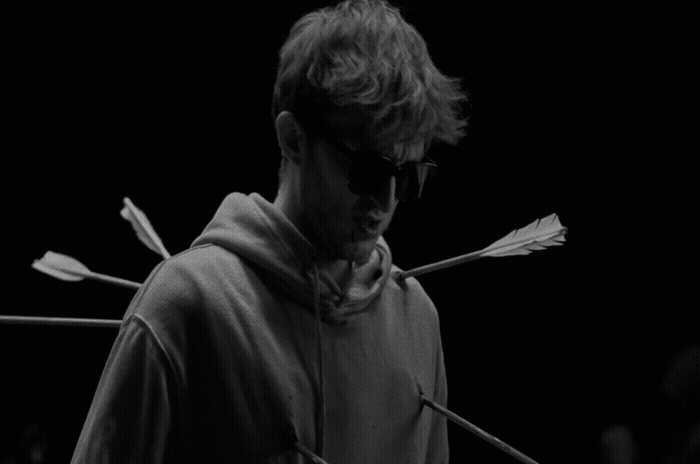 a man wearing sunglasses and a hoodie with arrows sticking out of it