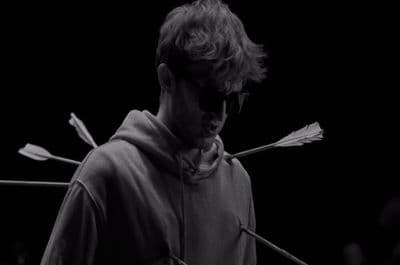 a man wearing sunglasses and a hoodie with arrows sticking out of it
