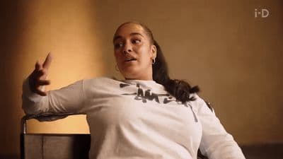 a woman sitting in a chair with her hand up
