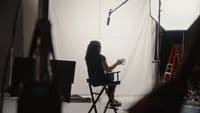 a woman sitting in a chair in front of a camera
