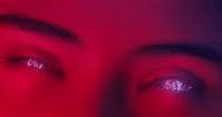 a close up of a person's eyes with a red background