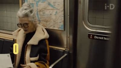 a woman sitting on a subway looking at her phone