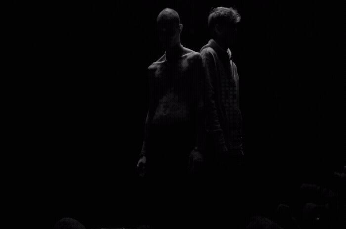 a couple of men standing next to each other in the dark