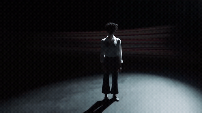a person standing in the dark with their shadow on the ground