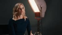a woman in a black dress standing in front of a light