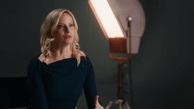 a woman in a black dress standing in front of a light