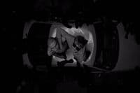 a couple of men standing next to each other in front of a car
