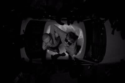 a couple of men standing next to each other in front of a car