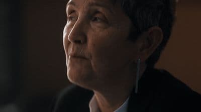 a woman in a suit and tie looking off into the distance