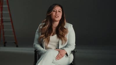 a woman sitting in a chair with a ladder behind her