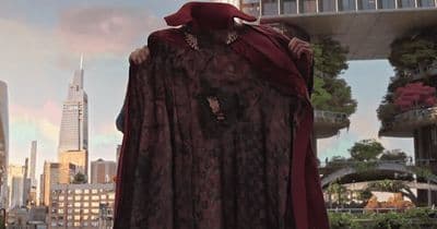 a statue of a woman wearing a red cape in front of a cityscape