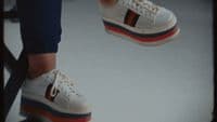 a person wearing white tennis shoes with red, white, and blue stripes