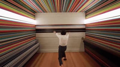 a person standing in front of a colorful wall