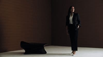 a woman standing in a room next to a bench