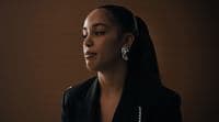 a woman wearing a black jacket and earrings