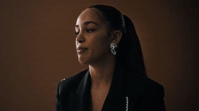 a woman wearing a black jacket and earrings