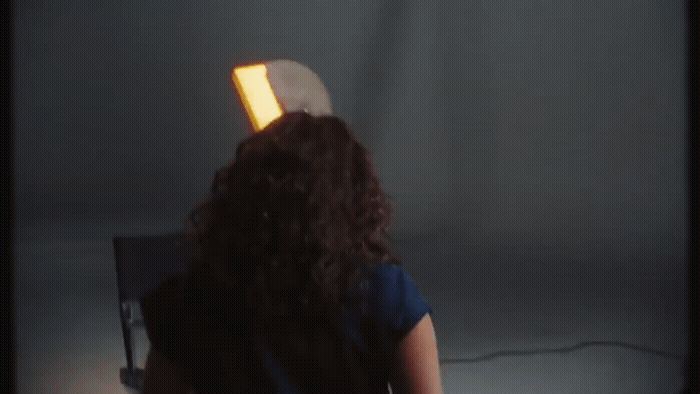 a woman standing in front of a wall with a light on her head