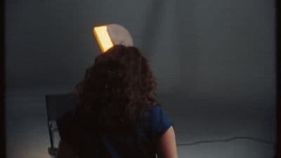 a woman standing in front of a wall with a light on her head