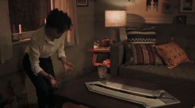 a woman standing in a living room next to a couch