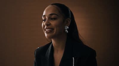 a woman wearing a black jacket and earrings