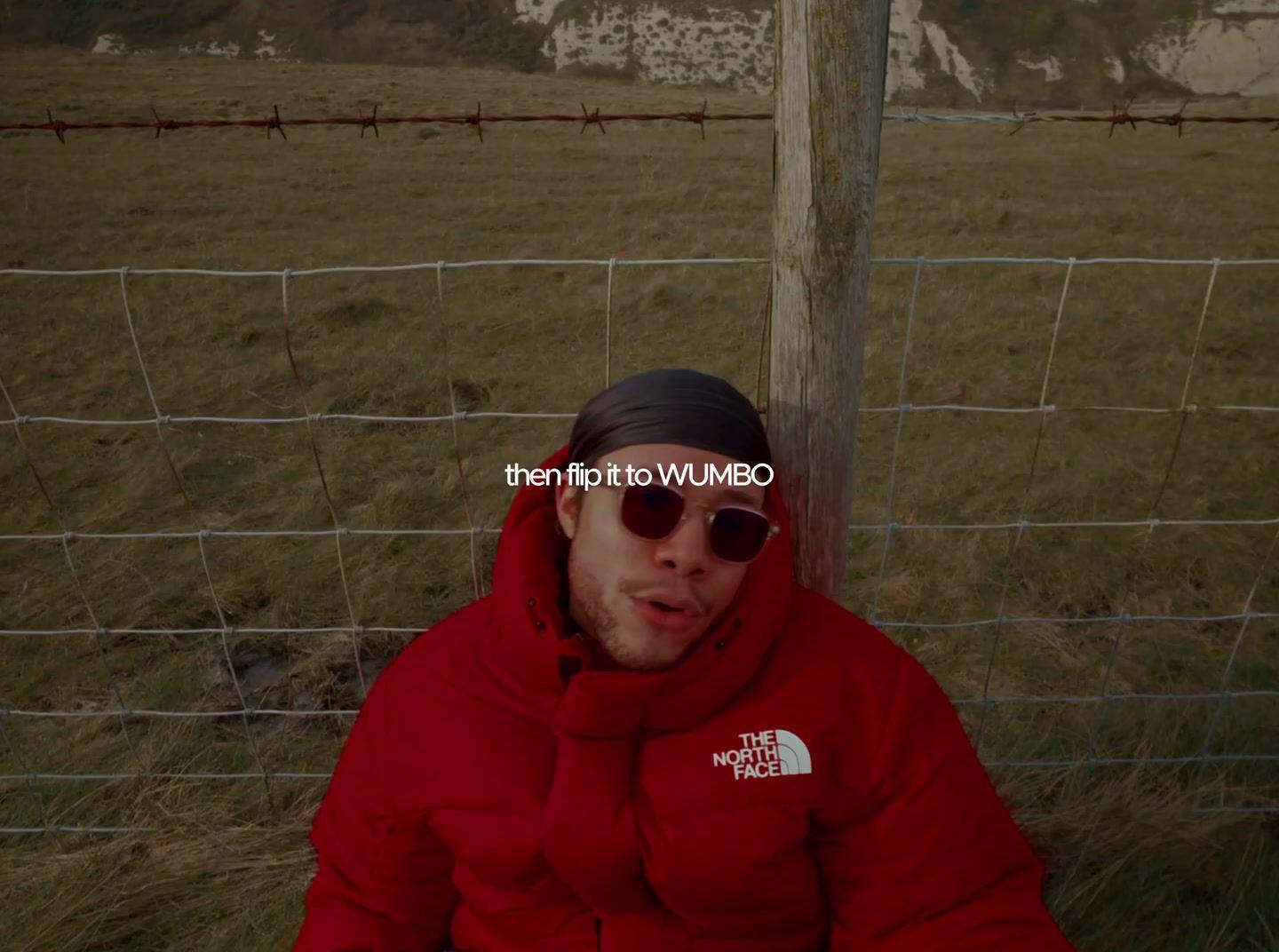 a man in a red jacket sitting in front of a fence
