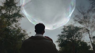 a man looking up at a soap bubble in the sky