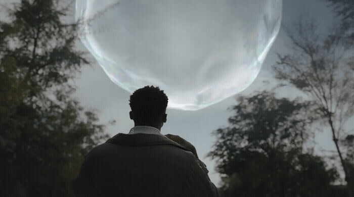 a man standing in front of a giant bubble