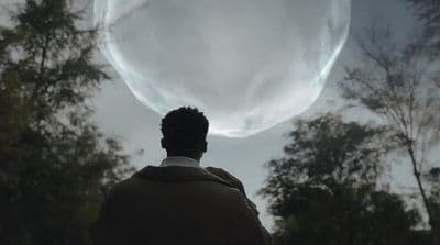 a man standing in front of a giant bubble