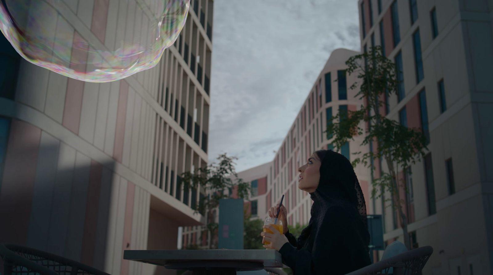 a woman in a black jacket blowing a bubble