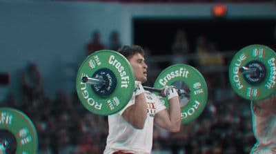 a man holding a barbell in front of a crowd