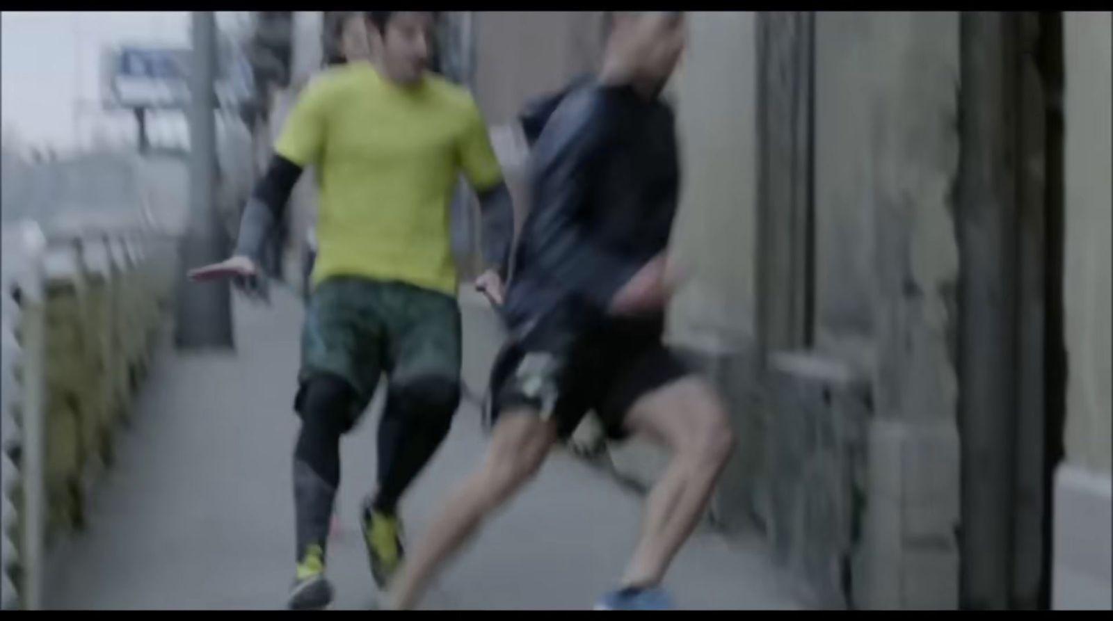 a couple of men running down a sidewalk