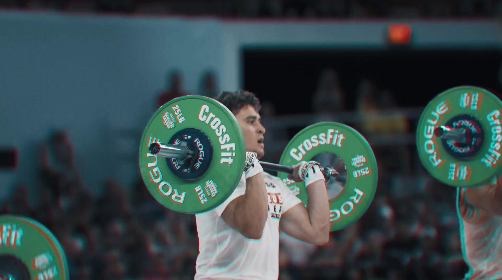 a man holding a barbell in front of a crowd
