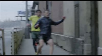 a man running down a sidewalk next to another man