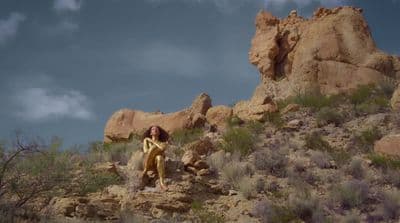a woman standing on top of a rocky hillside