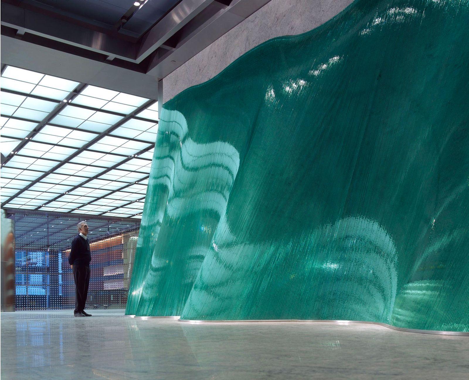a man standing in front of a large green piece of art