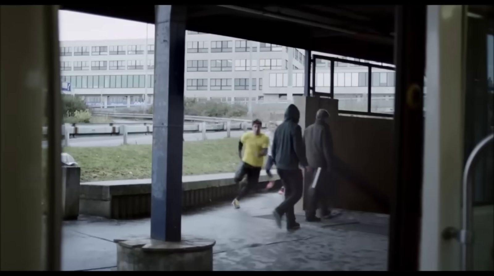 a group of people walking down a sidewalk next to a building