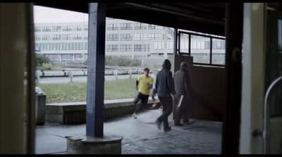 a group of people walking down a sidewalk next to a building