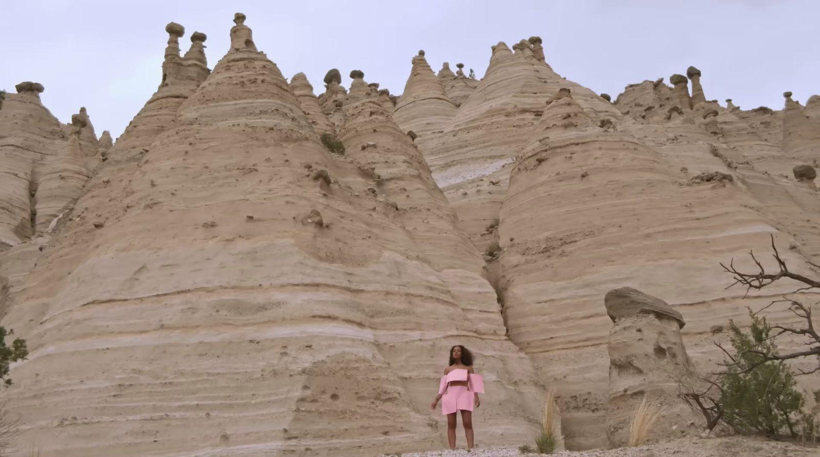 a woman standing in front of a large formation of rock formations