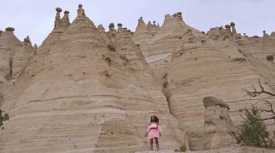 a woman standing in front of a large formation of rock formations