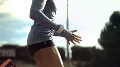 a woman in grey shirt and black shorts holding a tennis racquet