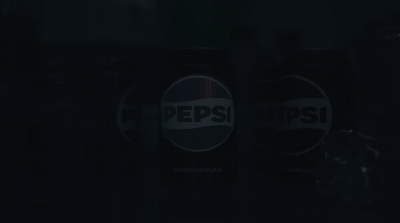 two pepsi cans sitting side by side in the dark