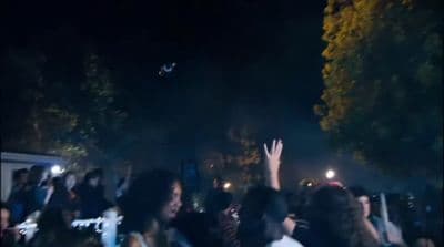 a crowd of people standing around each other at night