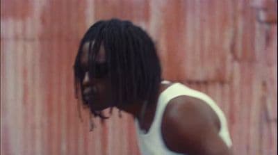 a man with dreadlocks standing in front of a wall