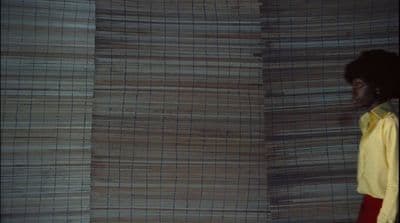 a woman standing in front of a wall of bamboo