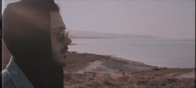 a man with glasses looking out over a body of water
