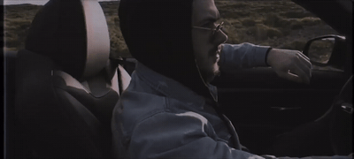 a man driving a car wearing a hoodie