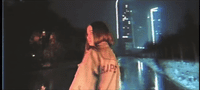 a woman standing in front of a city street at night